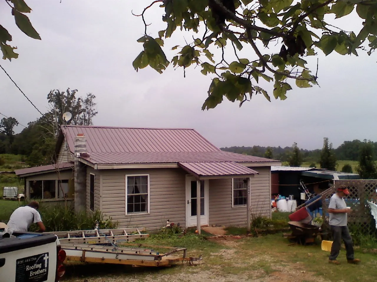 Crew finishing a mauve metal roof on a small farmhouse in Sullivans Island