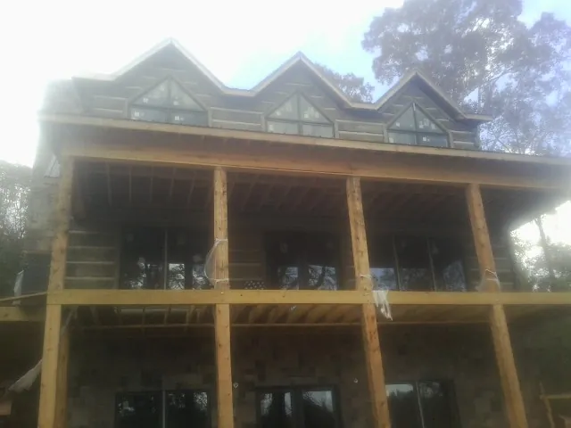 Dormers and porch framing on a large log home under construction — Roof Coating work by our crew in Sullivans Island
