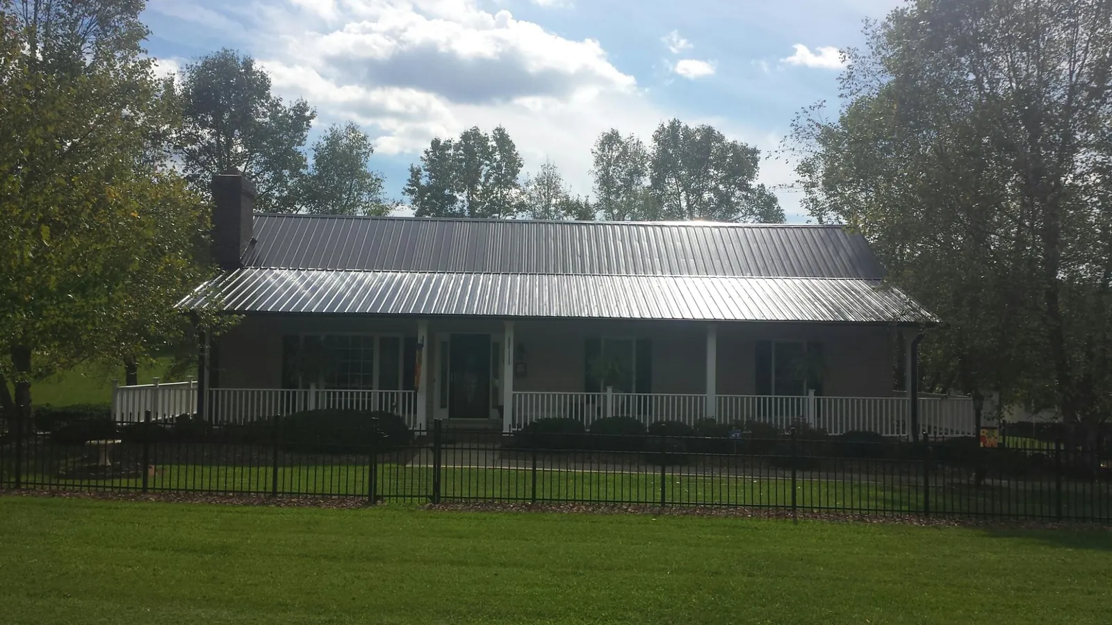 Gray metal roof on a brick ranch with a full width front porch — Gutter Guard Installation work by our crew in Sullivans Island