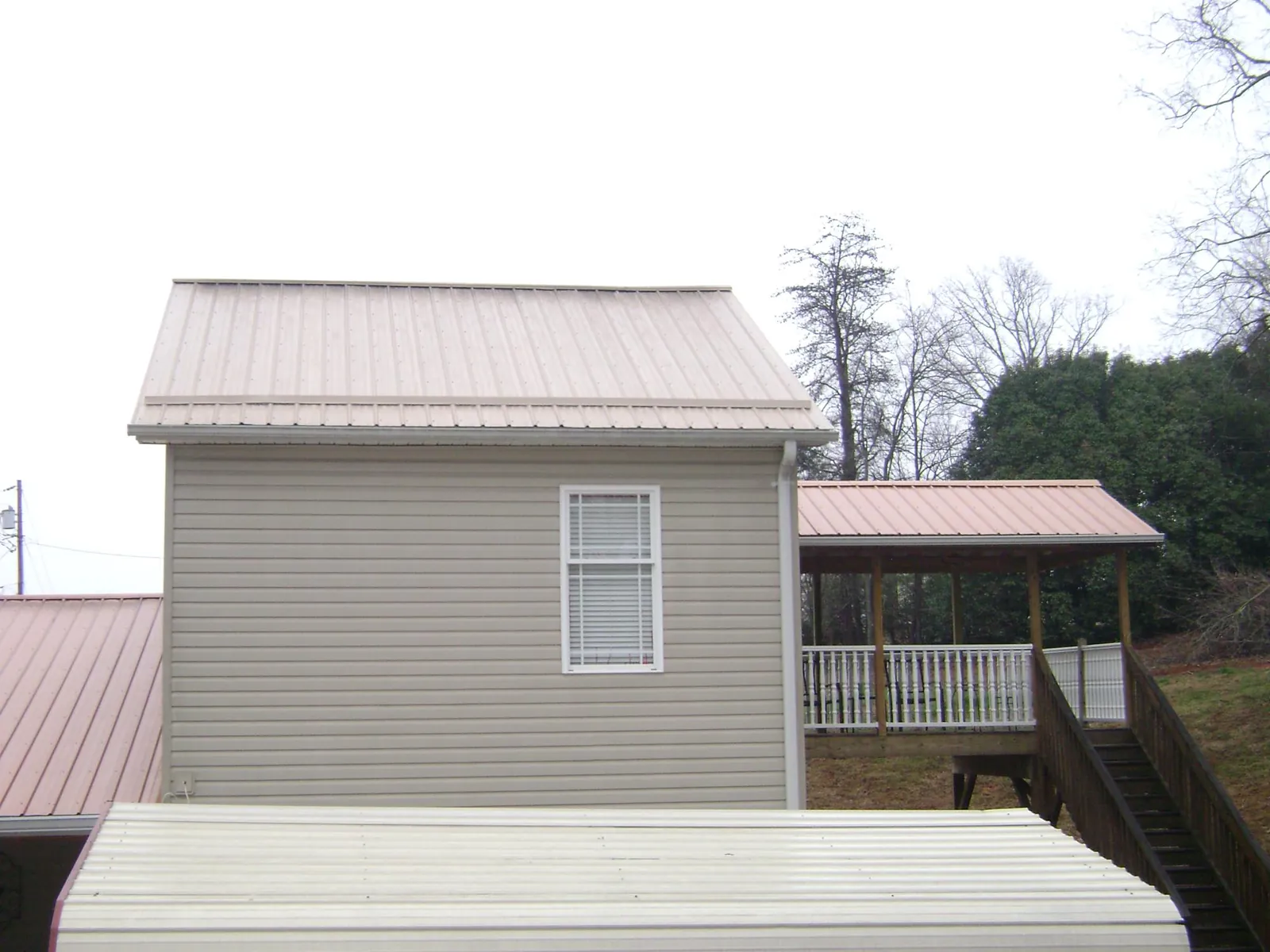 Tan metal roofs on a two story addition and attached porch, from a Roof Replacement job in Sullivans Island