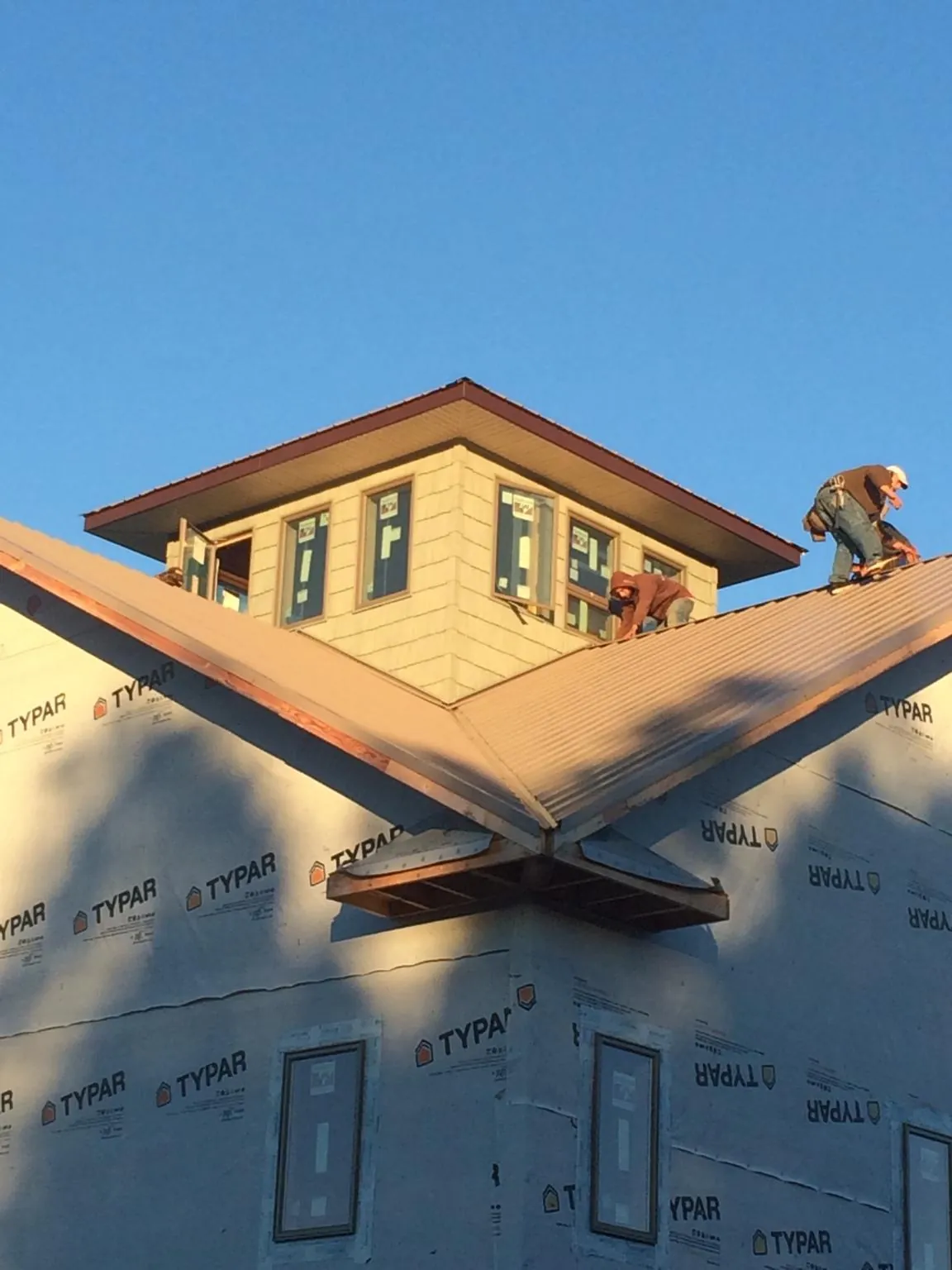Roofers working around a rooftop cupola on a new metal roof at sunset — Roof Waterproofing in Sullivans Island by Roofing Brothers